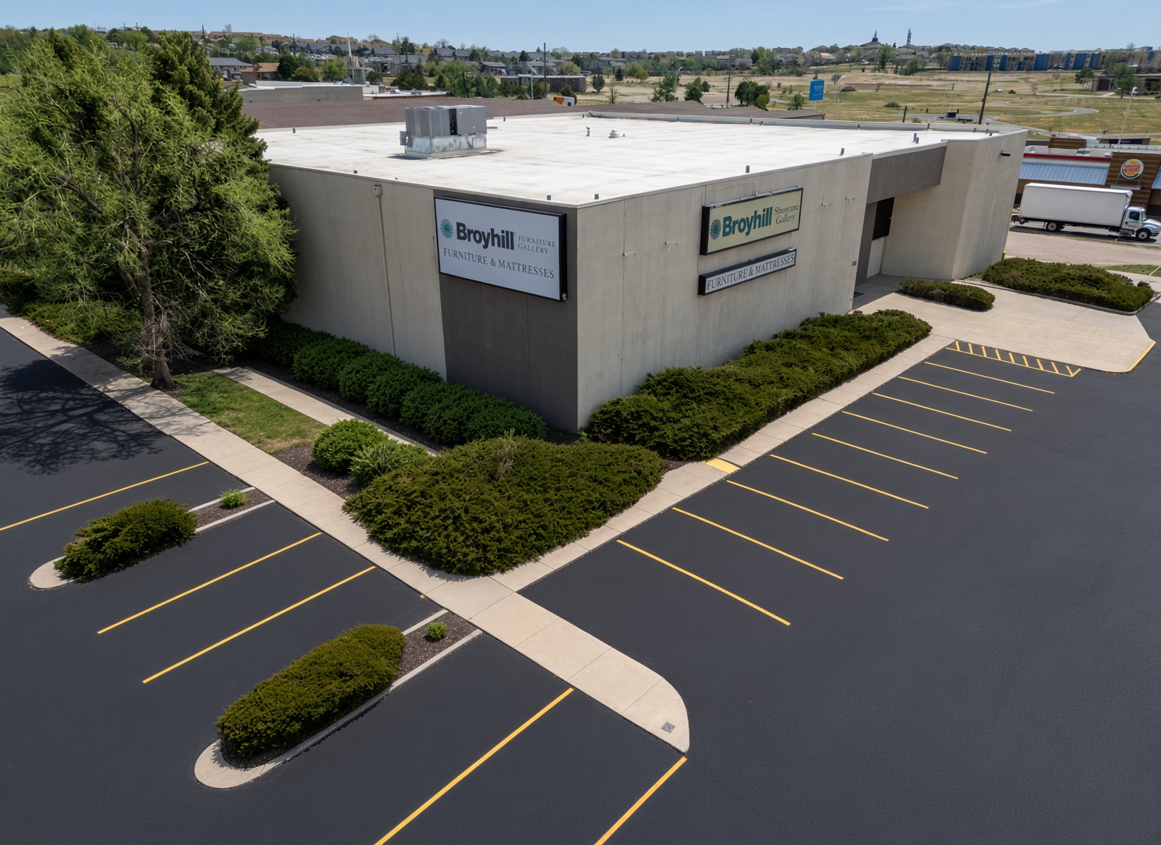 Signed corner elevation with landscape beds and striped parking.