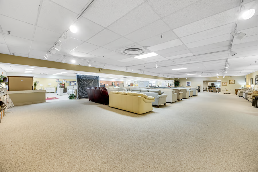 Open display area with track lighting on the soffit and a clear span of carpeted floor.