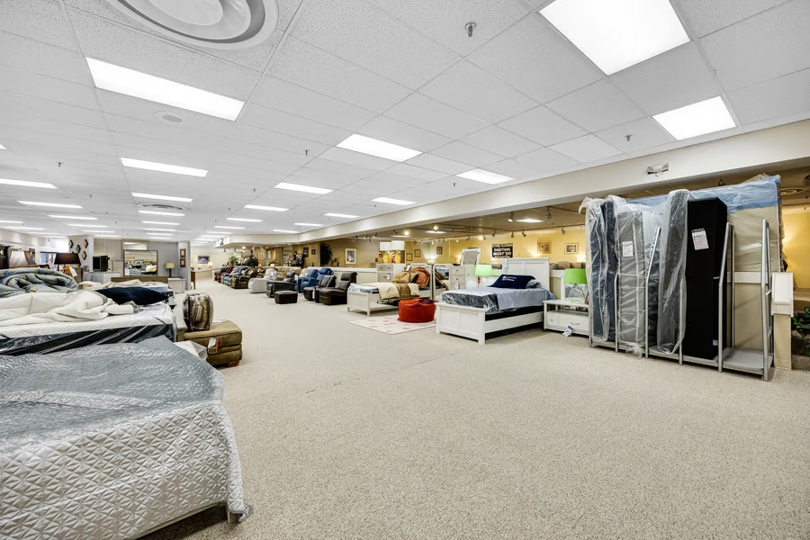 Long showroom bay with continuous ceiling grid, track lighting and clear sight lines to the rear.